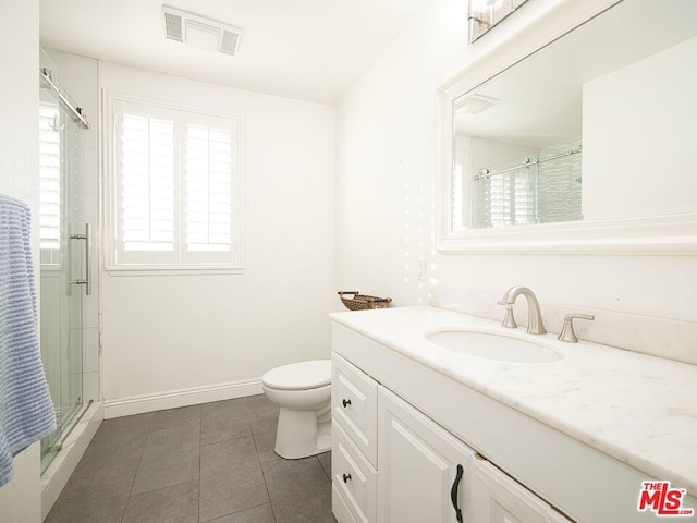 bathroom with tile patterned floors, vanity, toilet, and a shower with shower door