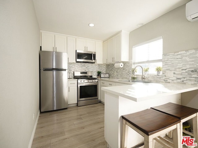 kitchen with white cabinetry, sink, kitchen peninsula, a kitchen bar, and appliances with stainless steel finishes