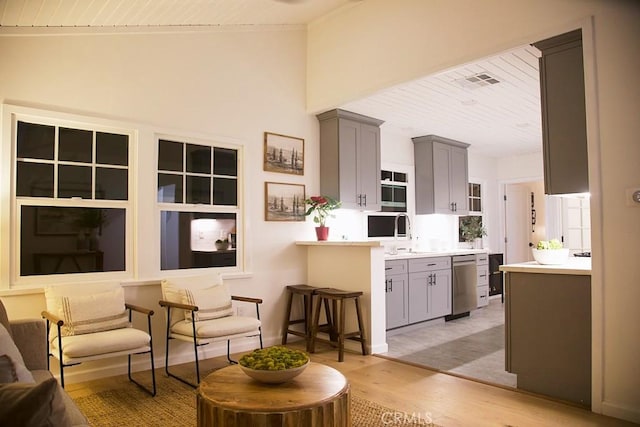 kitchen with gray cabinetry, lofted ceiling, light hardwood / wood-style floors, and wooden ceiling