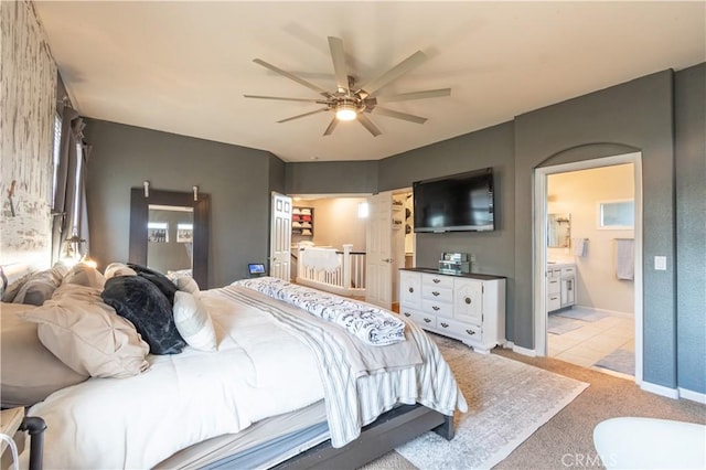 bedroom with ceiling fan, light colored carpet, and ensuite bathroom