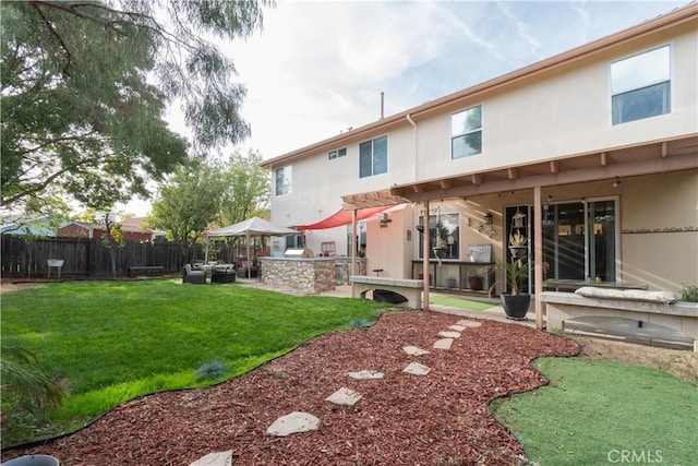 back of house featuring an outdoor kitchen, a lawn, and a patio