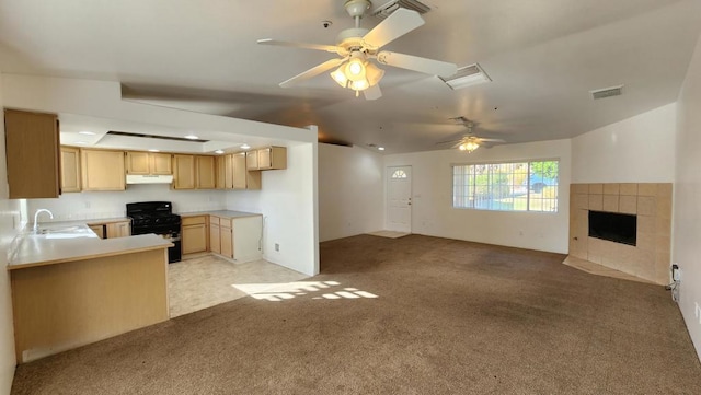 kitchen with kitchen peninsula, black range with gas stovetop, light colored carpet, sink, and light brown cabinets