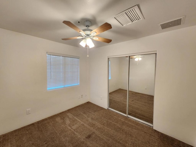 unfurnished bedroom featuring ceiling fan, a closet, and dark colored carpet