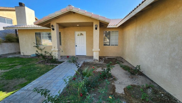 view of exterior entry featuring a lawn