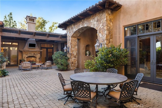 view of patio with french doors, an outdoor fireplace, and outdoor dining space