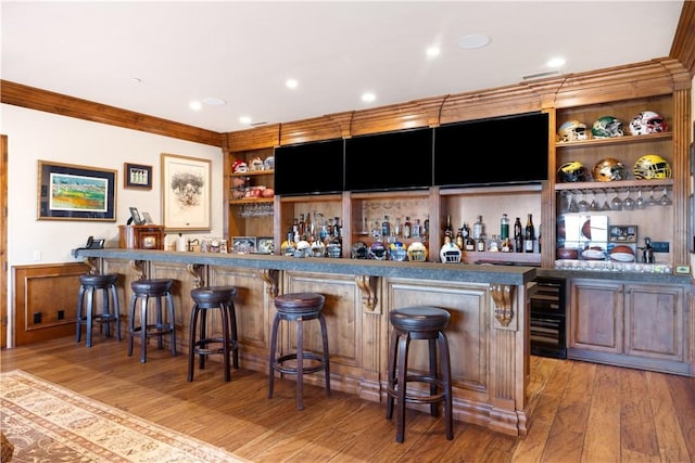 bar featuring a wainscoted wall, wet bar, built in features, and light wood finished floors