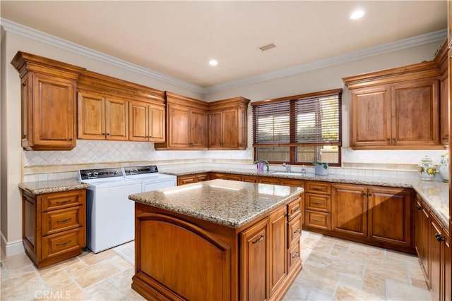 kitchen with washing machine and dryer, a center island, tasteful backsplash, and crown molding