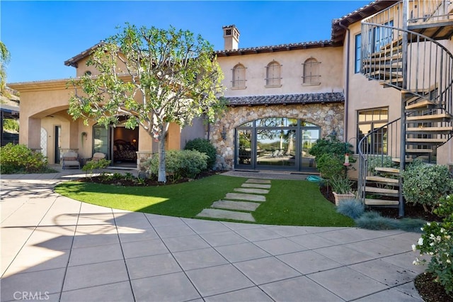 back of property featuring stucco siding, stone siding, and stairway