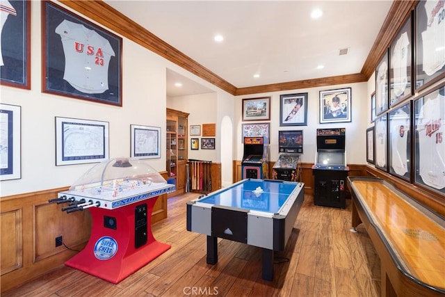 game room featuring arched walkways, wainscoting, visible vents, crown molding, and hardwood / wood-style flooring