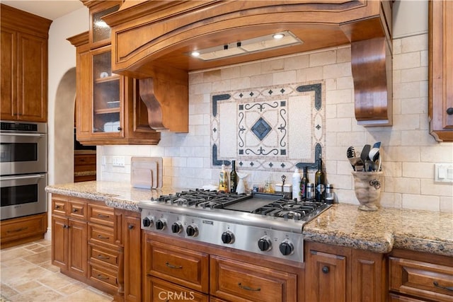 kitchen featuring backsplash, light stone countertops, and stainless steel appliances