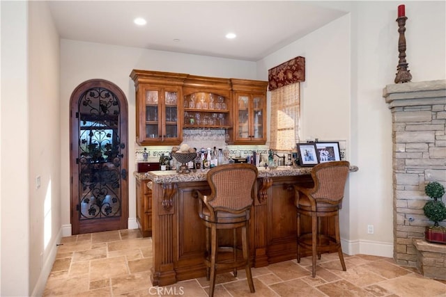 bar with stone tile floors, indoor wet bar, baseboards, and recessed lighting