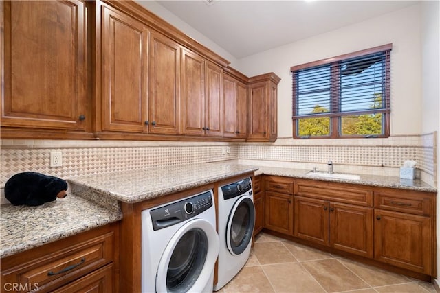 clothes washing area with cabinet space, independent washer and dryer, a sink, and light tile patterned floors