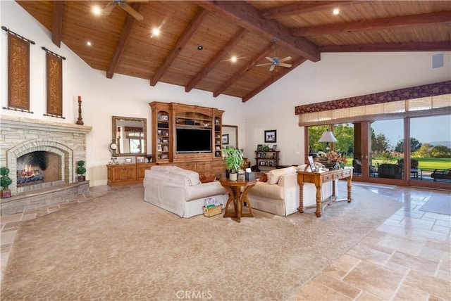 living area with high vaulted ceiling, a ceiling fan, a warm lit fireplace, stone tile floors, and wood ceiling