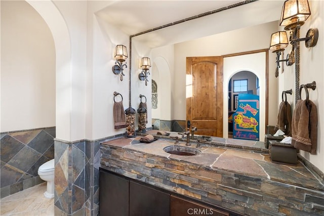 bathroom featuring vanity, tile walls, and toilet