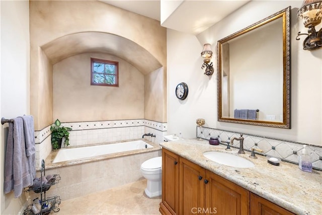 bathroom with tile patterned flooring, vanity, toilet, and tiled tub