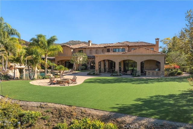 back of house with a patio and a lawn