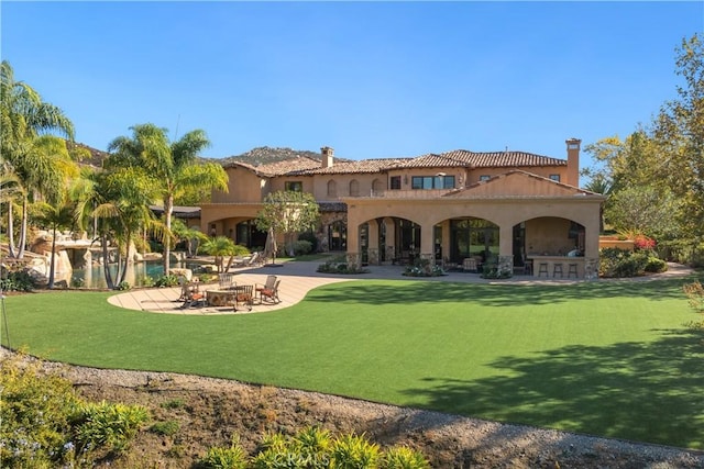rear view of house featuring stucco siding, a lawn, and a patio