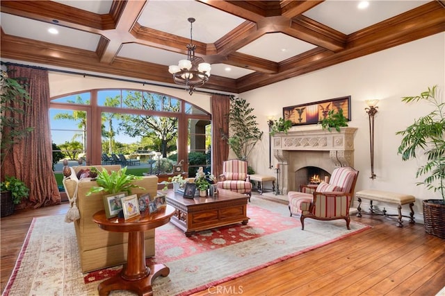 living room with light wood-type flooring, ornamental molding, coffered ceiling, a notable chandelier, and beamed ceiling