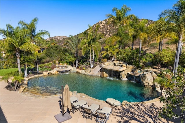 view of pool with a mountain view, pool water feature, and a patio