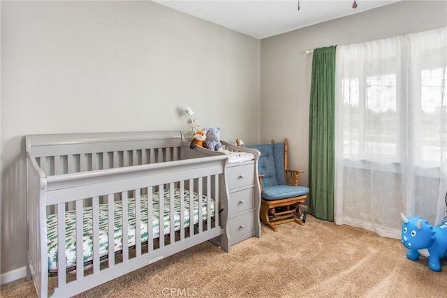 bedroom featuring light carpet and a crib