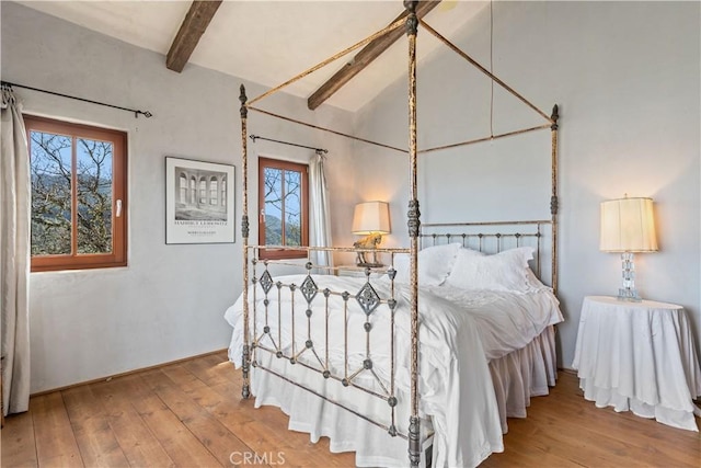 bedroom with multiple windows, light hardwood / wood-style flooring, and lofted ceiling with beams