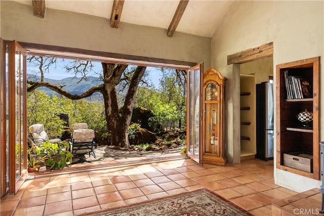 entryway with a mountain view, beamed ceiling, light tile patterned flooring, and high vaulted ceiling