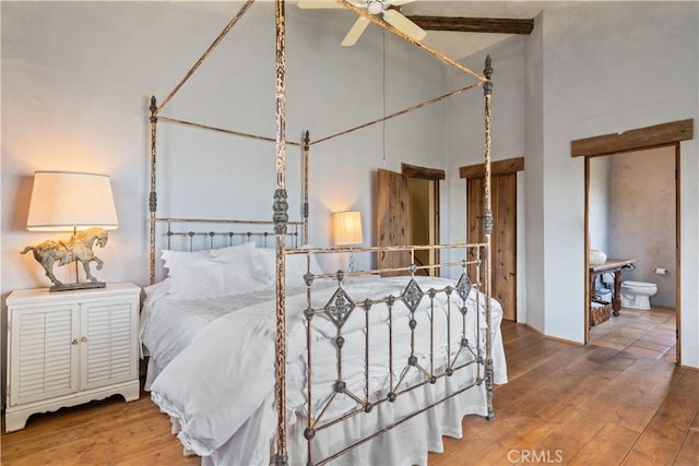 bedroom featuring ensuite bathroom, ceiling fan, wood-type flooring, and a high ceiling