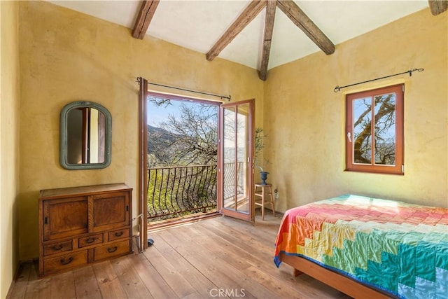 bedroom featuring multiple windows, hardwood / wood-style floors, vaulted ceiling with beams, and access to exterior