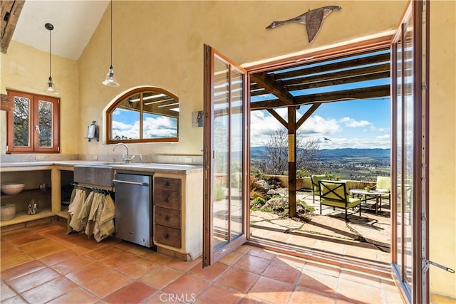 kitchen featuring dishwasher, sink, a mountain view, a towering ceiling, and pendant lighting