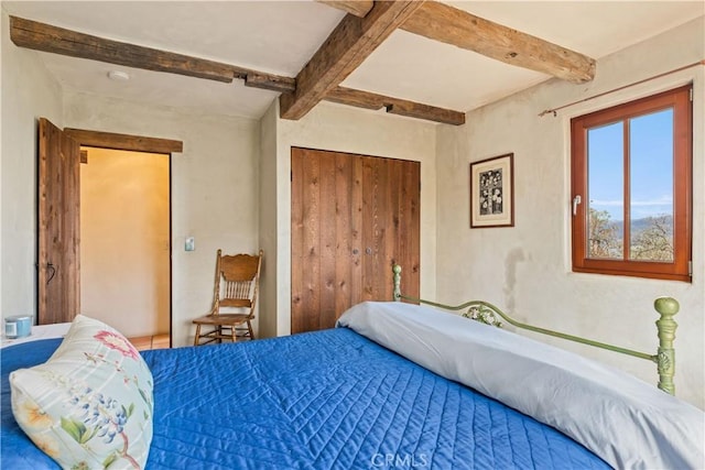 bedroom featuring a closet and beamed ceiling