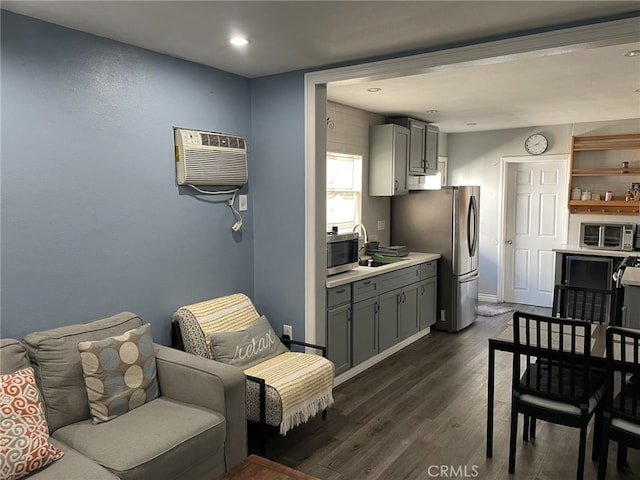 kitchen with appliances with stainless steel finishes, sink, an AC wall unit, gray cabinets, and dark hardwood / wood-style floors