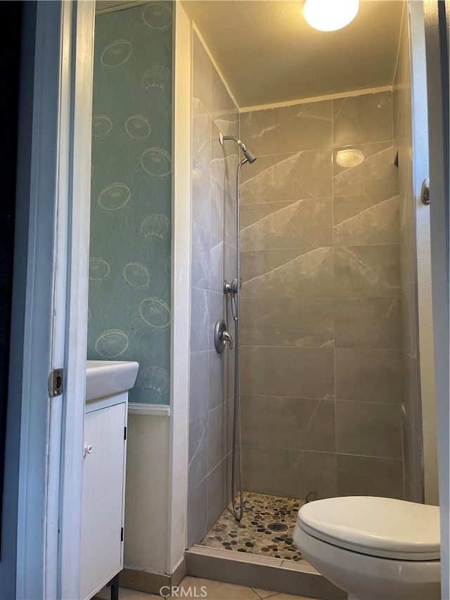 bathroom featuring a tile shower, vanity, and toilet