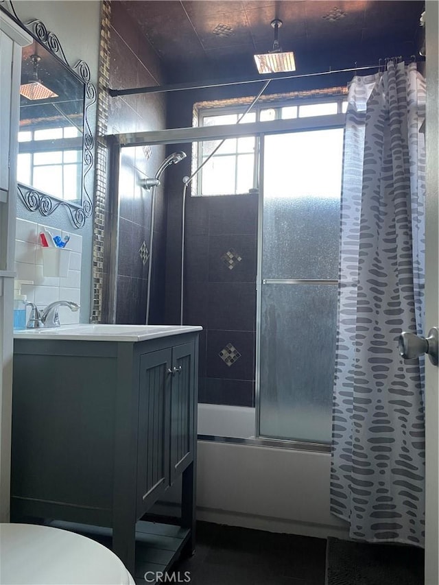 full bathroom featuring vanity, toilet, combined bath / shower with glass door, and a wealth of natural light