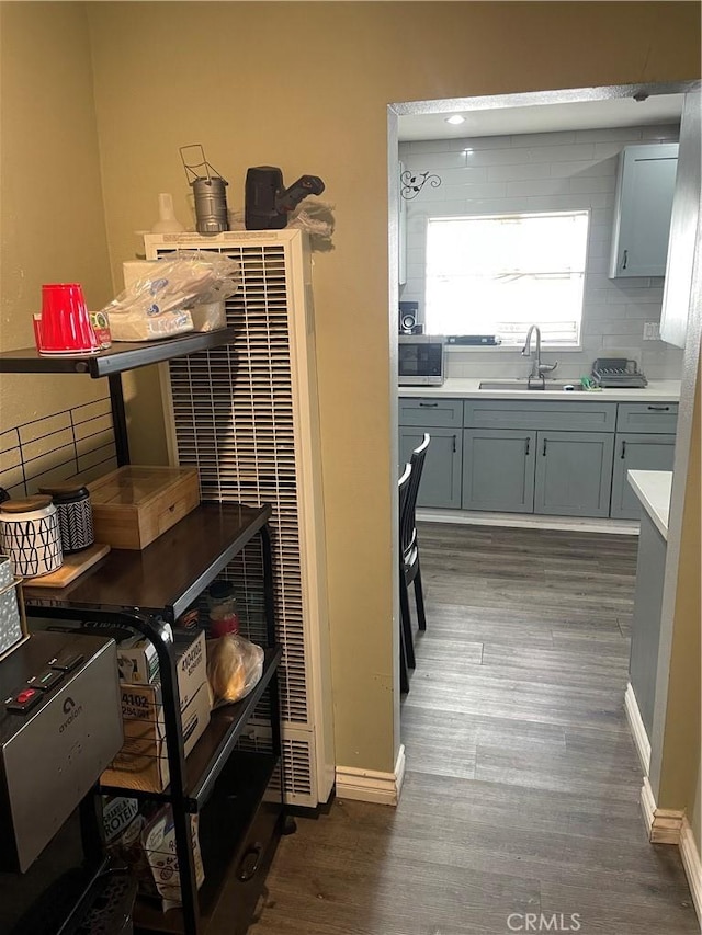 kitchen with tasteful backsplash, gray cabinets, sink, and dark wood-type flooring