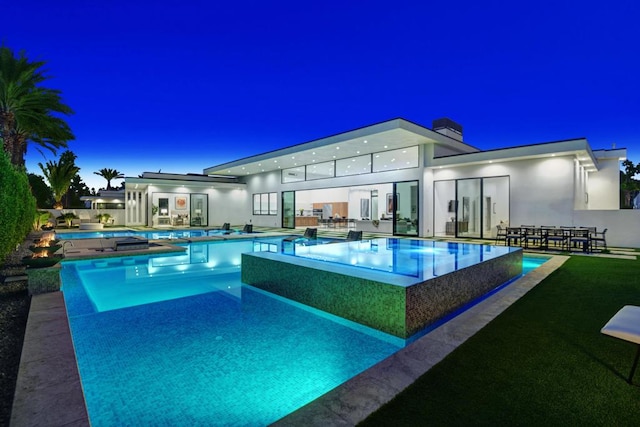 pool at dusk with a patio area and a jacuzzi