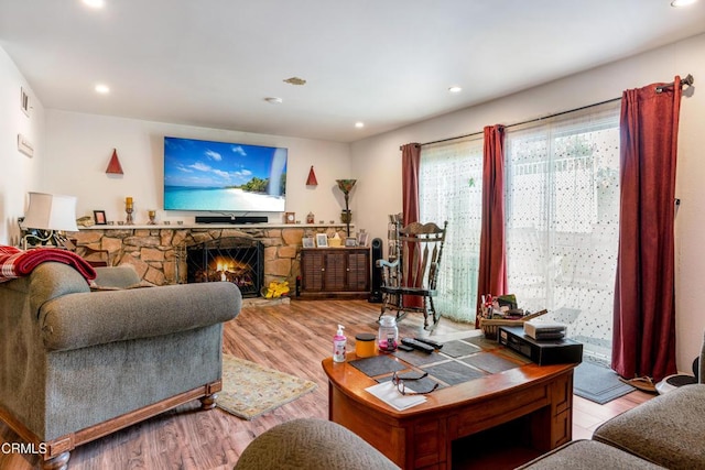 living room with a stone fireplace and light hardwood / wood-style floors