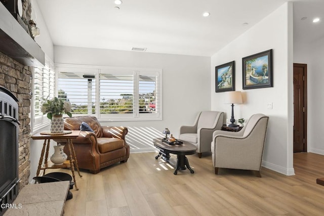 living room featuring light hardwood / wood-style floors and a stone fireplace