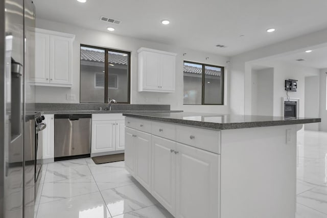 kitchen with dishwasher, white cabinetry, a kitchen island, and sink