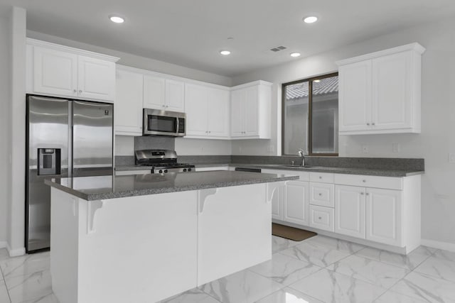 kitchen featuring white cabinetry, a center island, sink, a kitchen bar, and appliances with stainless steel finishes