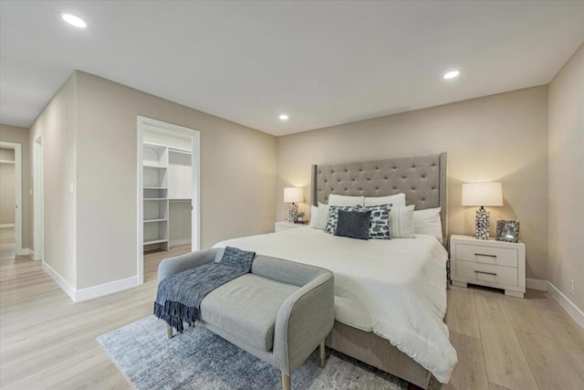 bedroom with a spacious closet and light hardwood / wood-style floors