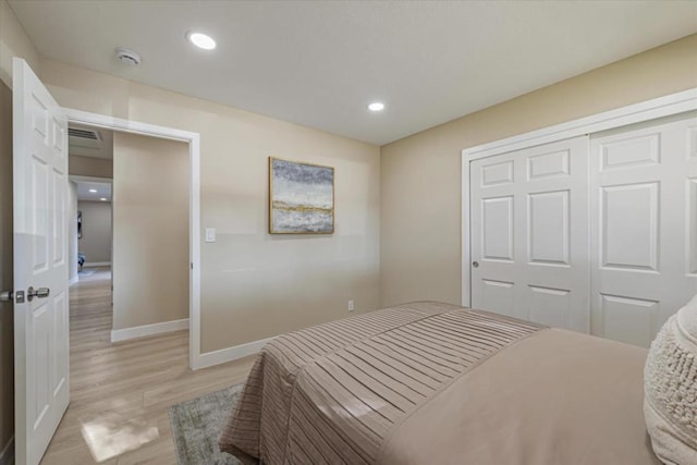 bedroom with light hardwood / wood-style floors and a closet