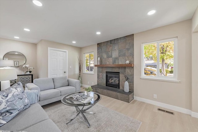 living room featuring a tile fireplace and light hardwood / wood-style floors