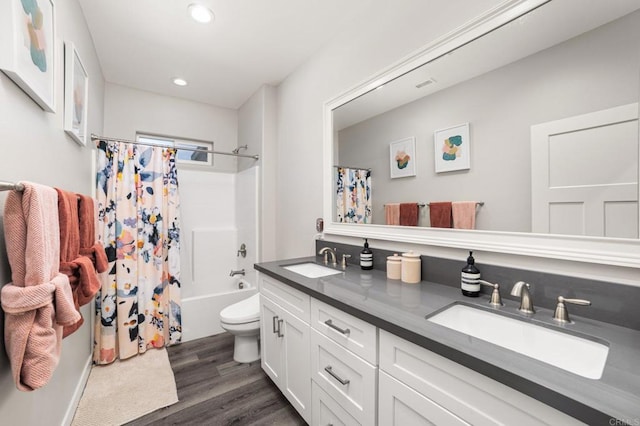 full bathroom with hardwood / wood-style floors, vanity, toilet, and shower / tub combo