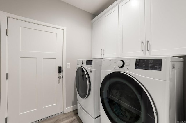 laundry room featuring cabinets, light hardwood / wood-style flooring, and washer and clothes dryer