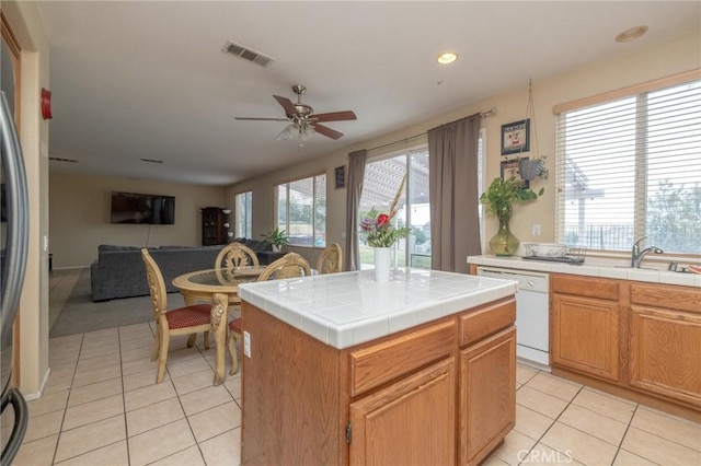 kitchen featuring light tile patterned floors, tile countertops, ceiling fan, white dishwasher, and a kitchen island