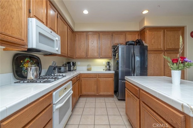 kitchen featuring light tile patterned floors, tile counters, and white appliances