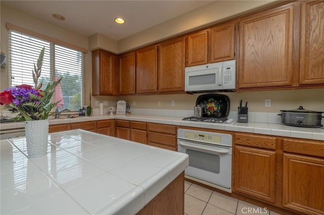 kitchen featuring light tile patterned flooring, tile counters, and white appliances