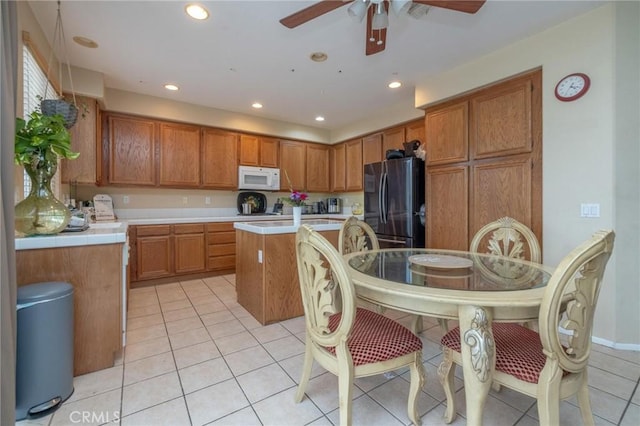 kitchen featuring ceiling fan, light tile patterned floors, fridge, and a center island