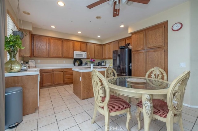 kitchen with light tile patterned flooring, a center island, refrigerator, and ceiling fan