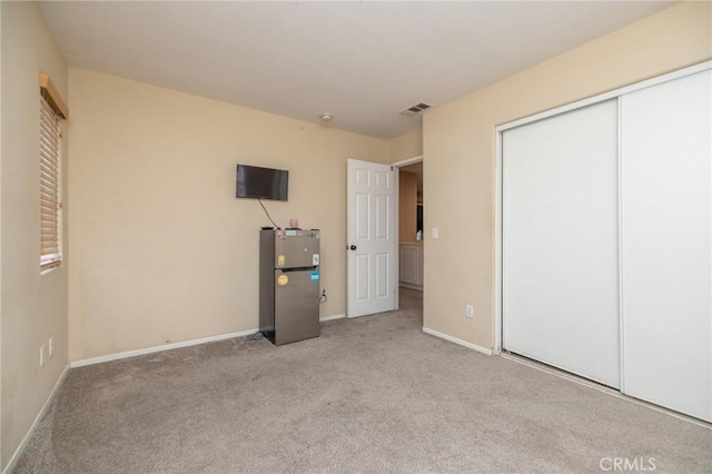 unfurnished bedroom with a closet and light colored carpet